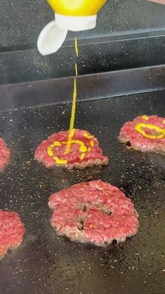 hamburger patties being cooked on a grill with yellow liquid coming out of the top