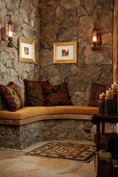 a stone wall with two framed pictures on it and a bench in the corner between them