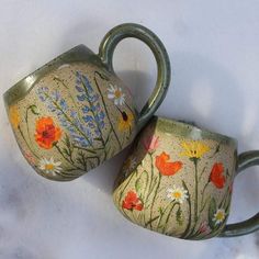 two ceramic mugs with painted flowers on them