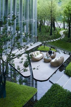 a man sitting on a couch in the middle of a garden with trees and grass