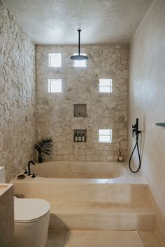 a white bathroom with stone walls and flooring