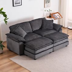 a large gray couch sitting on top of a wooden floor next to a white rug