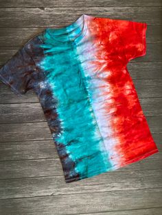 a red, white and blue t - shirt sitting on top of a wooden floor