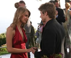 a man in a suit talking to a woman in a red dress