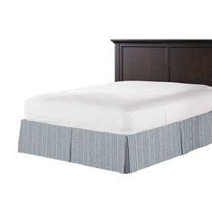 a bed with a white and blue bedspread next to a wooden headboard