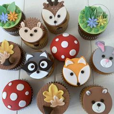 cupcakes decorated like animals and mushrooms on a table