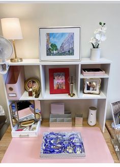 a desk with various items on it and a lamp in the corner next to it