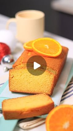 a loaf of orange pound cake sitting on top of a table next to sliced oranges