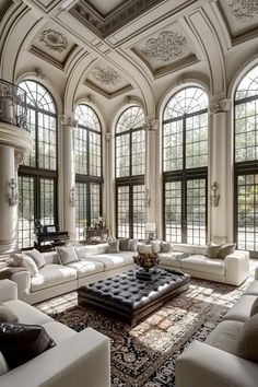 a large living room with white couches and lots of windows on the ceiling,