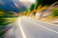 blurry photograph of an empty road with trees in the background