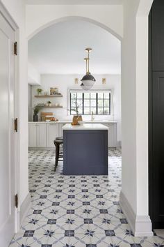 an archway leads into a kitchen with black and white tile flooring on the walls