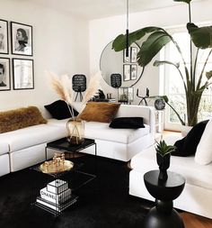 a living room filled with white furniture and pictures on the wall above it's coffee table