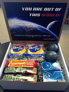 an open box filled with candy on top of a table next to a sign that says you are out of this world