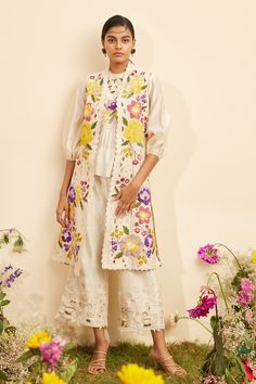 Ivory chanderi long jacket with all over multi color floral applique, thread embroidery and cut work embroidered details.
Components: 1
Pattern: Embroidered
Type Of Work: Floral Applique, Cut Work and Thread Work
Neckline: Open
Sleeve Type: Sleeveless
Fabric: Chanderi
Color: Ivory
Other Details: 
Cut work hem
Panelled jacket
Note: The inner top and pant worn by the model is not for sale
Occasion: Party - Aza Fashions Patch Work Top, Long Kurti Patterns, Panel Jacket, Linen Embroidery, Floral Patches, Ivory Fabric, Balloon Sleeve Top, Fashion Forecasting, Applique Shirts