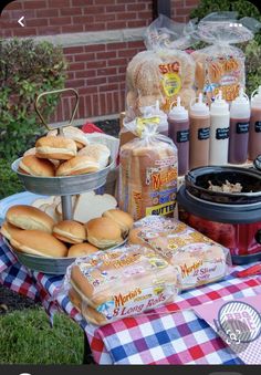 an assortment of hot dogs and buns on a picnic table with other food items