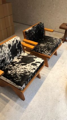 two wooden chairs with black and white cowhide upholsters in a room