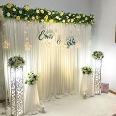 the wedding stage is decorated with white flowers and greenery for an elegant touch to the venue