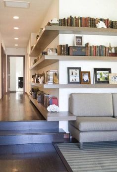 a living room filled with furniture and bookshelves next to a doorway that leads to a hallway