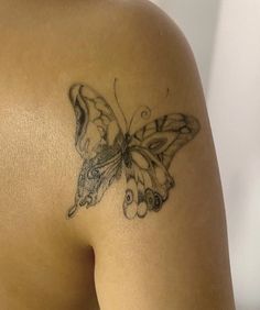 a woman's back with a butterfly tattoo on her left shoulder and right arm