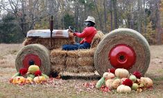 a man sitting on top of a hay cart filled with pumpkins