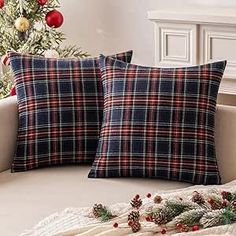 two plaid pillows sitting on top of a couch next to a christmas tree