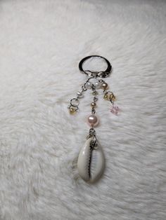 a keychain with an animal's shell and beads hanging from it on a white fur surface