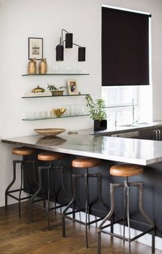 a kitchen island with three stools in front of it and two hanging lights above