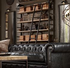 a black leather couch sitting in front of a book shelf