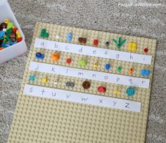 a lego board with letters and numbers on it next to a plastic container filled with magnets