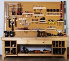 a workbench with lots of tools hanging on the wall