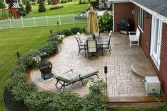 an outdoor patio with chairs, tables and umbrellas in the grass next to a house