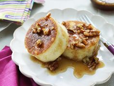 two pancakes on a white plate topped with walnuts