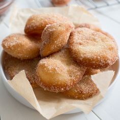 some sugared donuts are on a white plate