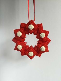 a lego christmas ornament hanging from a red ribbon on a white wall,