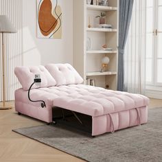 a pink couch sitting on top of a wooden floor next to a book shelf filled with books