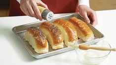 a person pouring salt onto rolls on a pan