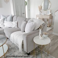 a living room filled with lots of furniture next to a white table and mirror on the wall