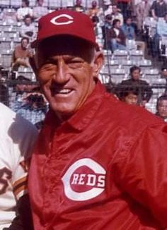 two men in red jackets standing next to each other at a baseball game with fans watching