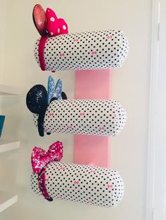 three minnie mouse hair clips are hanging on the wall next to a pink shelf with polka dots