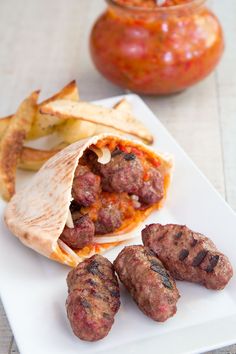 there is a plate with some meatballs and chips next to a jar of sauce