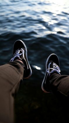 a person's feet with their shoes on by the water