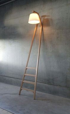 a wooden ladder leaning against a wall with a light on it's side and a lamp hanging from the ceiling