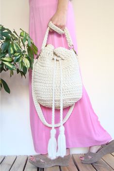 a woman in pink dress holding a white handbag with tassels on it