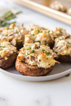 a white plate topped with stuffed mushrooms covered in cheese