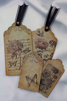 three tags with birds and flowers on them are hanging from black leather handles, along with two pairs of scissors