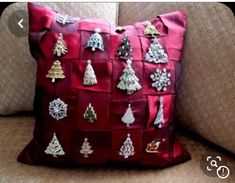 a red pillow with christmas decorations on it sitting on a couch next to a cushion