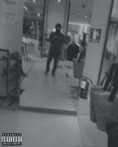 black and white photograph of a man walking through a clothing store