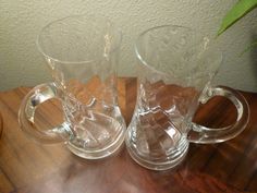 two clear glass mugs sitting on top of a wooden table