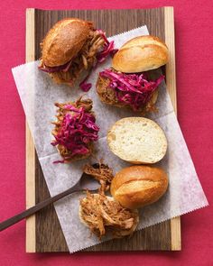 four pulled pork sliders with coleslaw and bread on a wooden cutting board