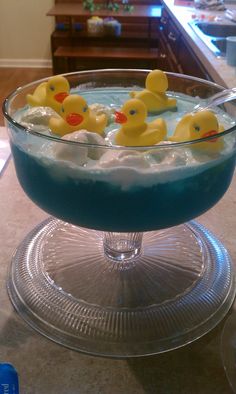 a bowl filled with blue liquid and yellow rubber ducks in it on top of a counter